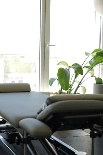 Behandlungsliege am Fenster mit Pflanze und viel Tageslicht.